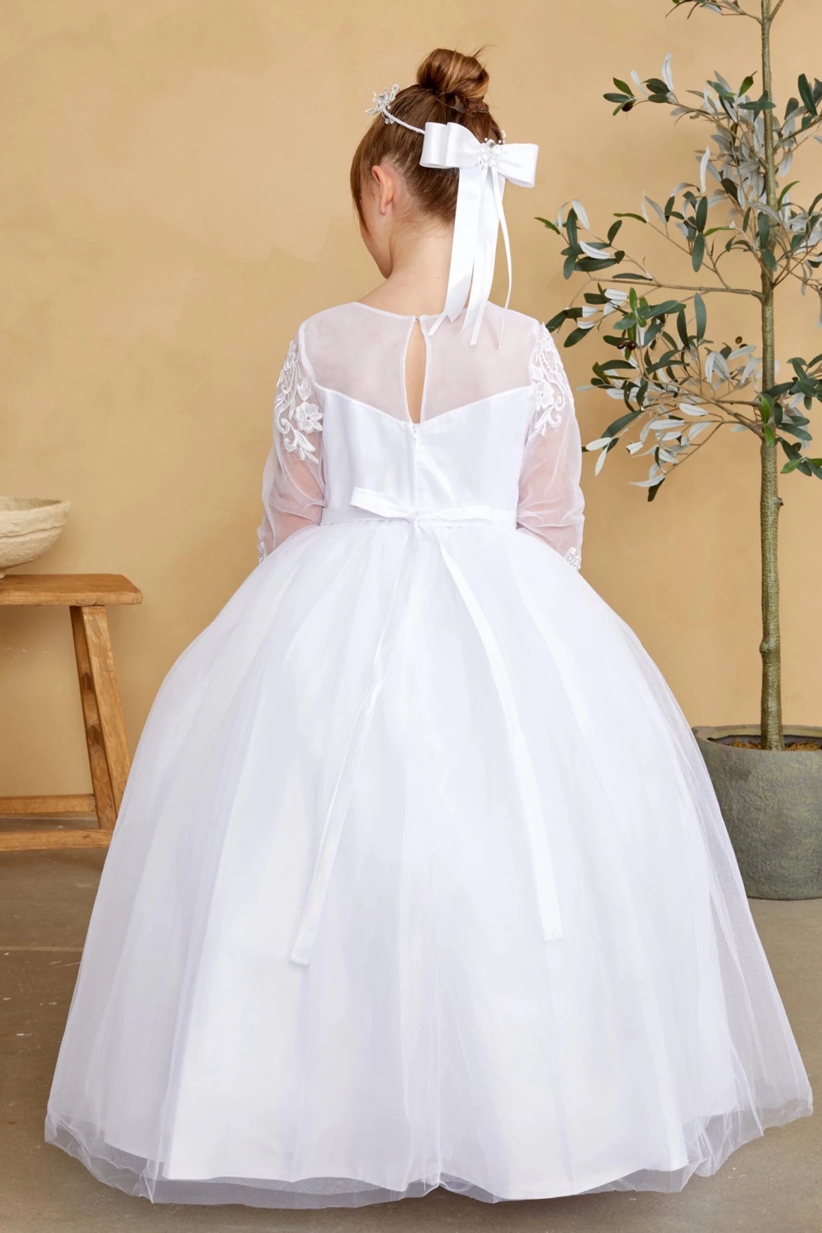 Emphasis on a small back waist bow of the white flower girl dress.
