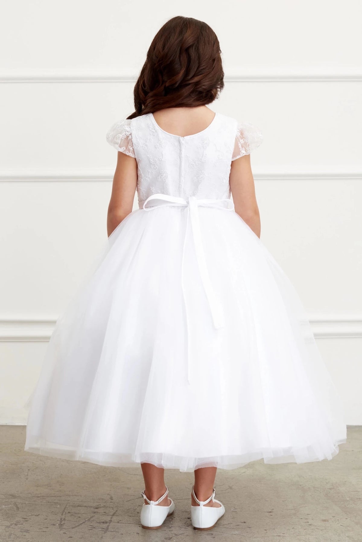 Behind the waist, an off-white flower girl dress has a narrow tied bow.