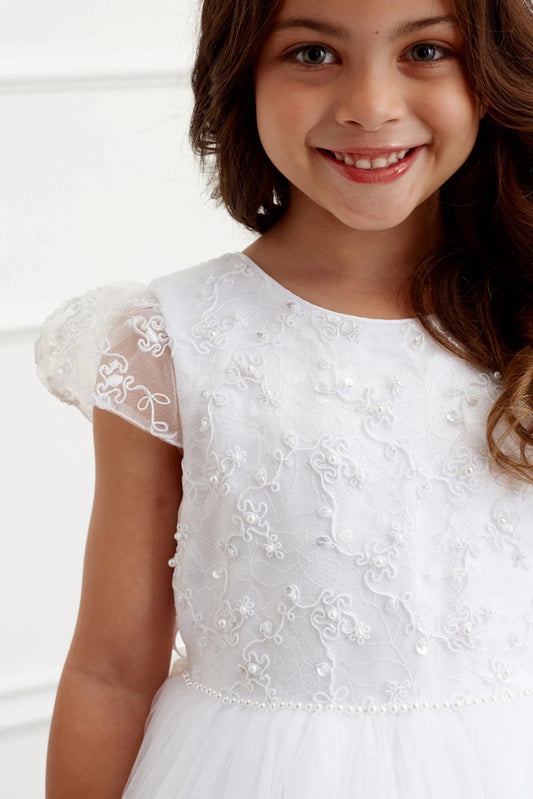 Swirling embroidery fills the off-white flower girl dress's sheer cap sleeve.