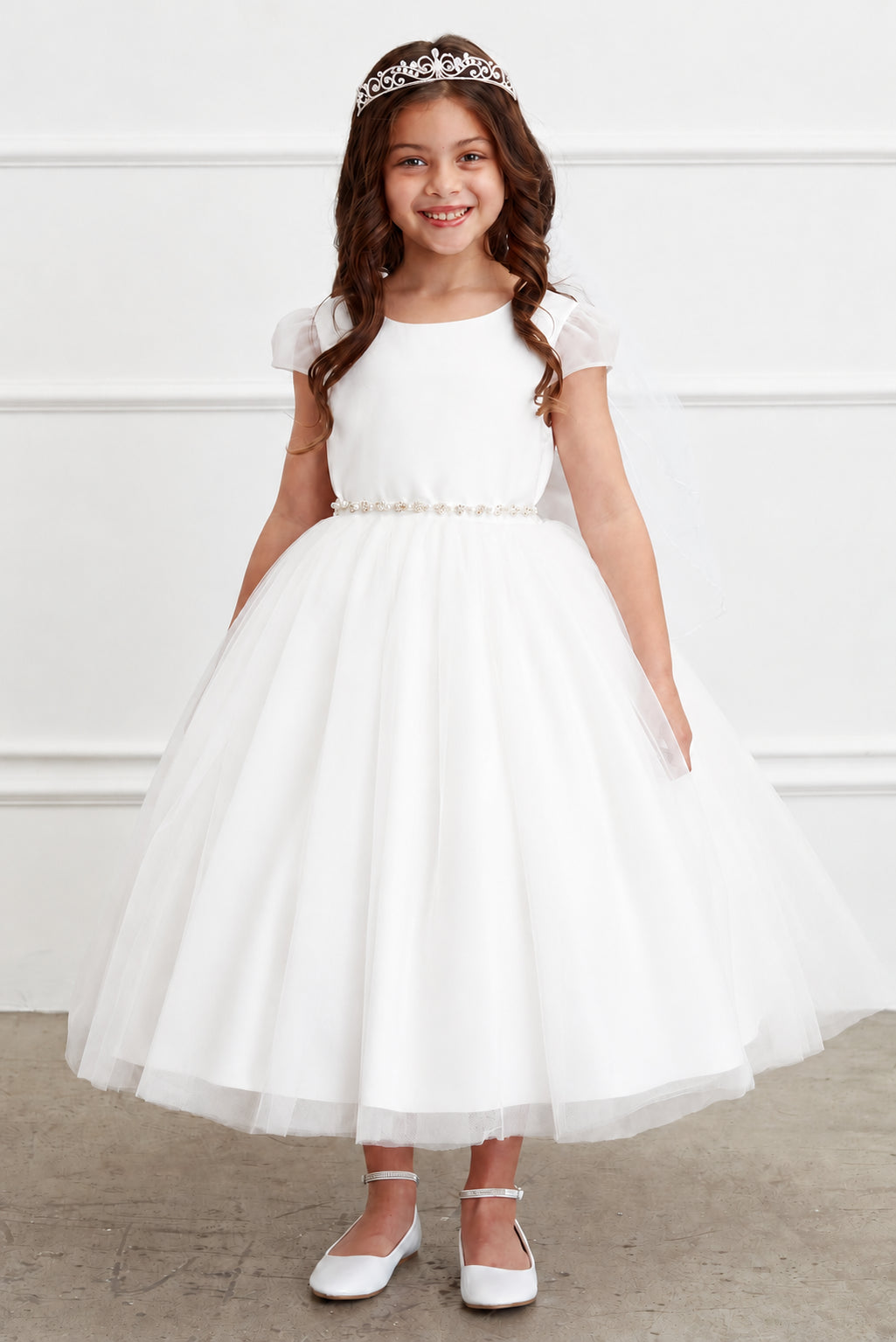 A jeweled belt separates the off-white flower girl dress's plain bodice.