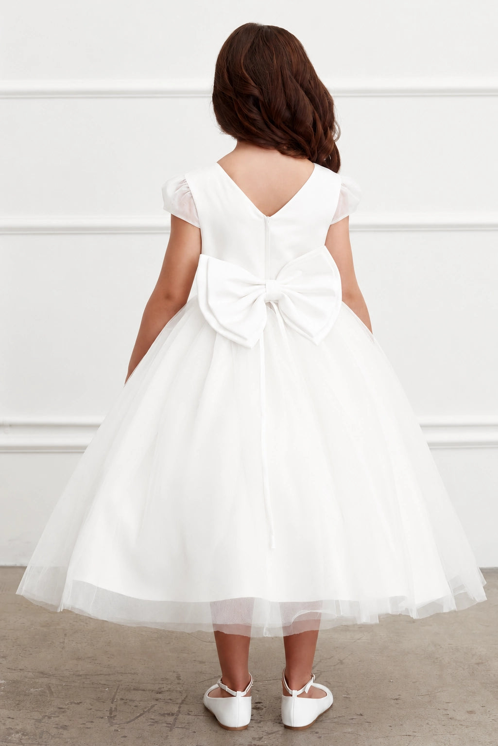large satin back bow of an off-white flower girl tulle dress. cap sleeves