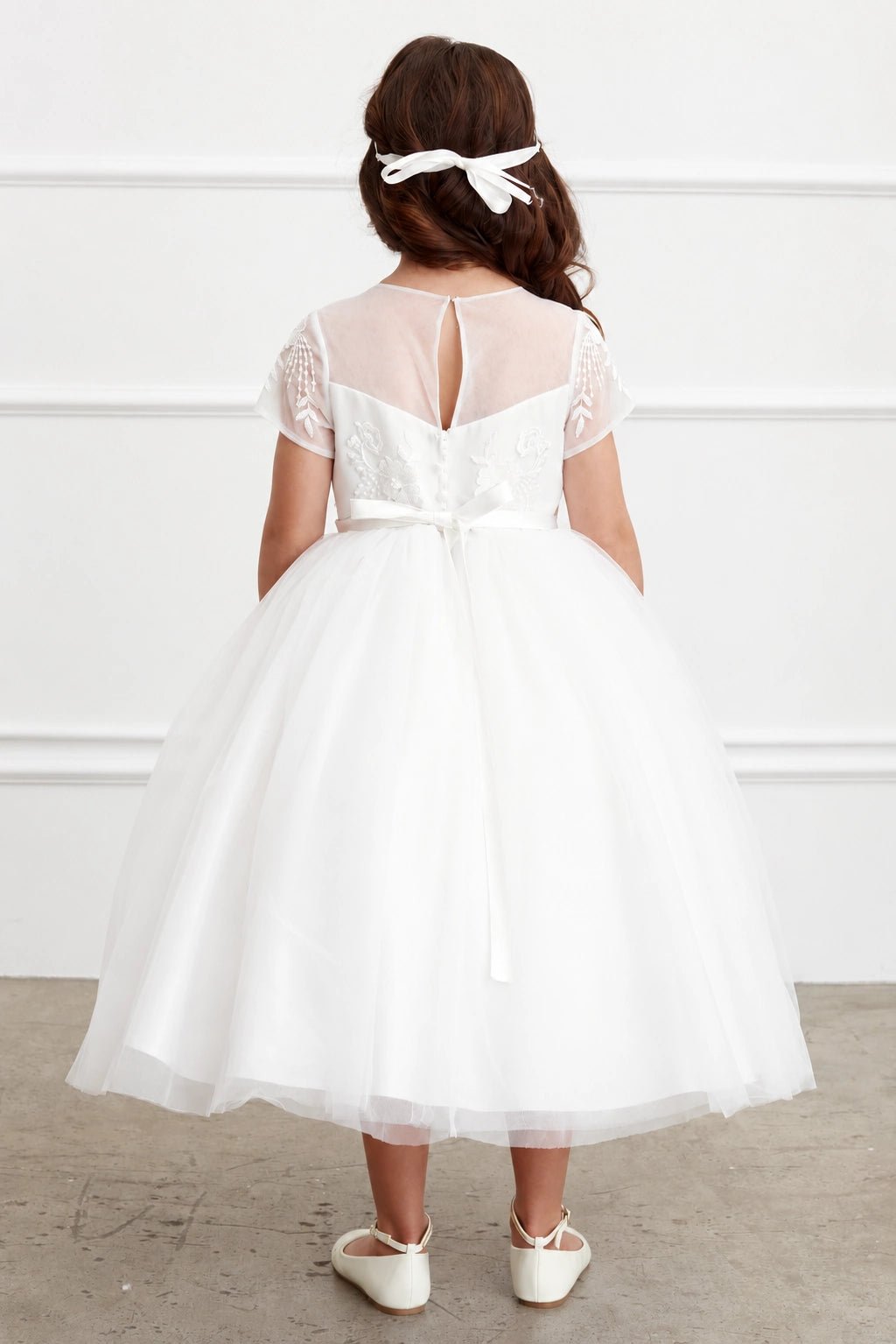 Defined by a small back waist bow, this off-white flower girl dress.