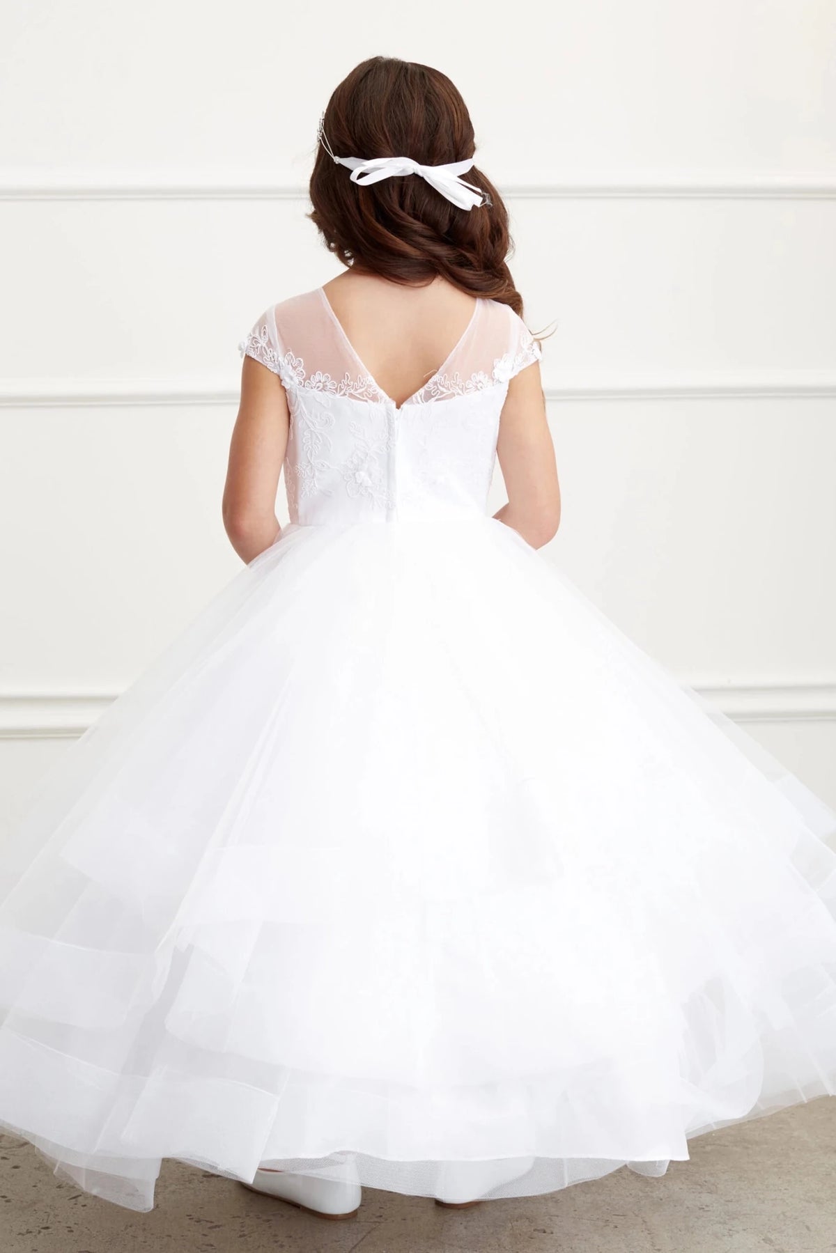 In view: a satin back bow of a white flower girl dress.