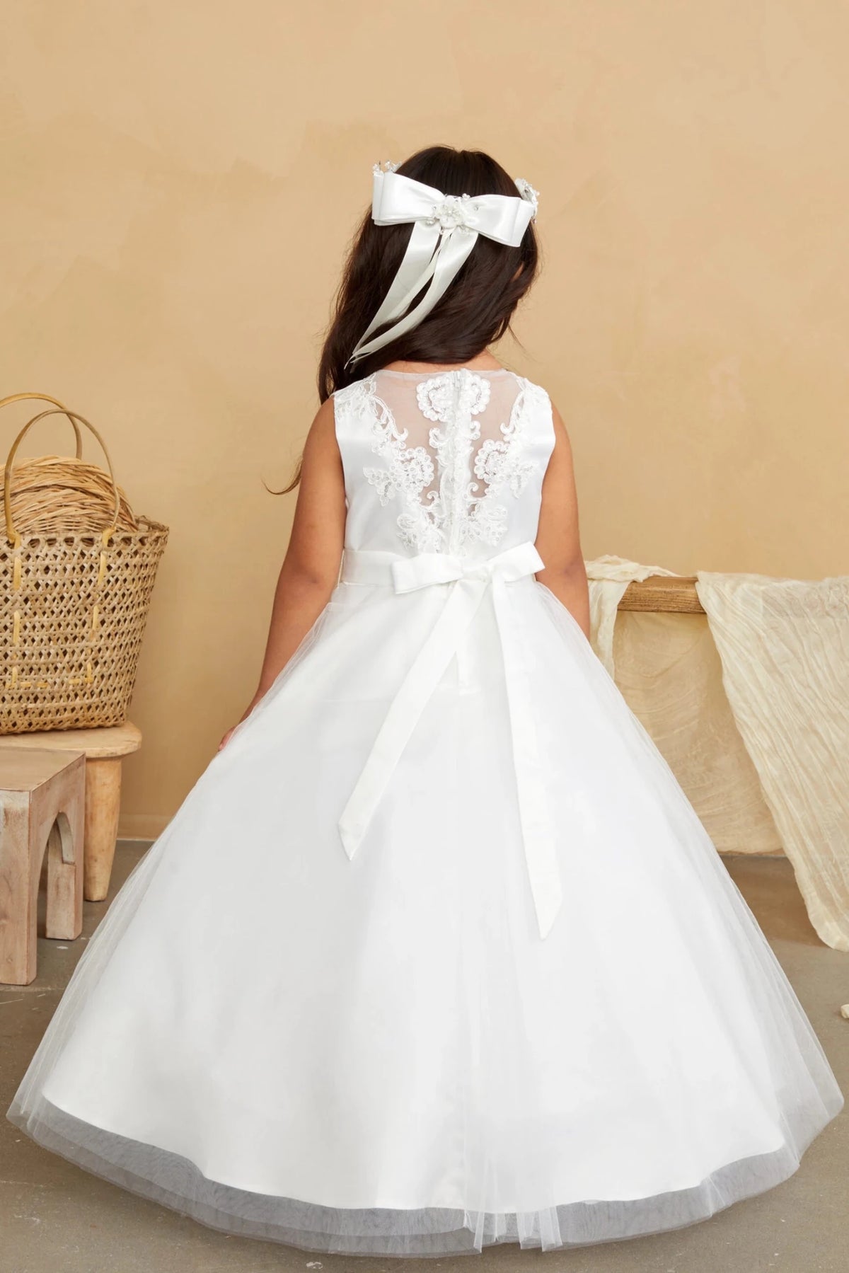Leafy embroidery descends the off-white flower girl dress's sheer back.