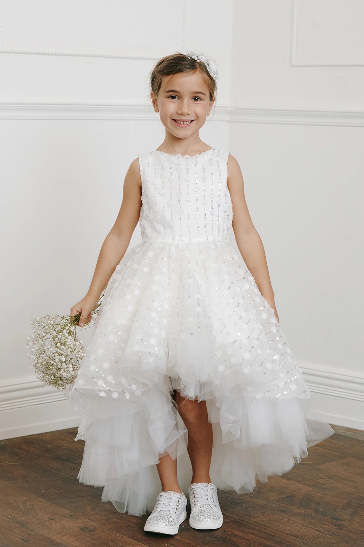 Shorter at the front, this off-white flower girl dress reveals tulle ruffles.