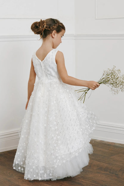 A V back tops the off-white flower girl dress's long, dotted skirt.