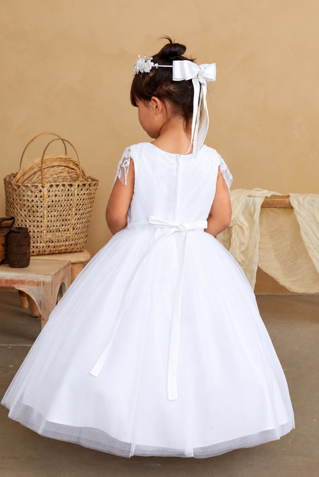 Long satin tails hang from the white flower girl dress's back bow.