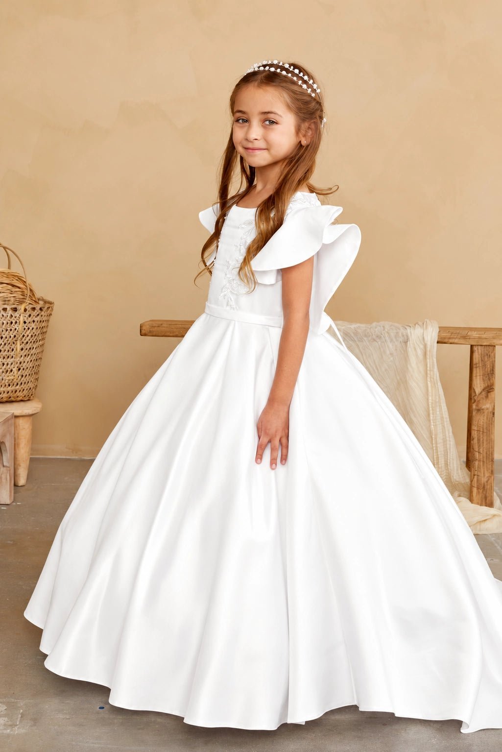 Sculpted flutter sleeves frame this off-white flower girl dress.
