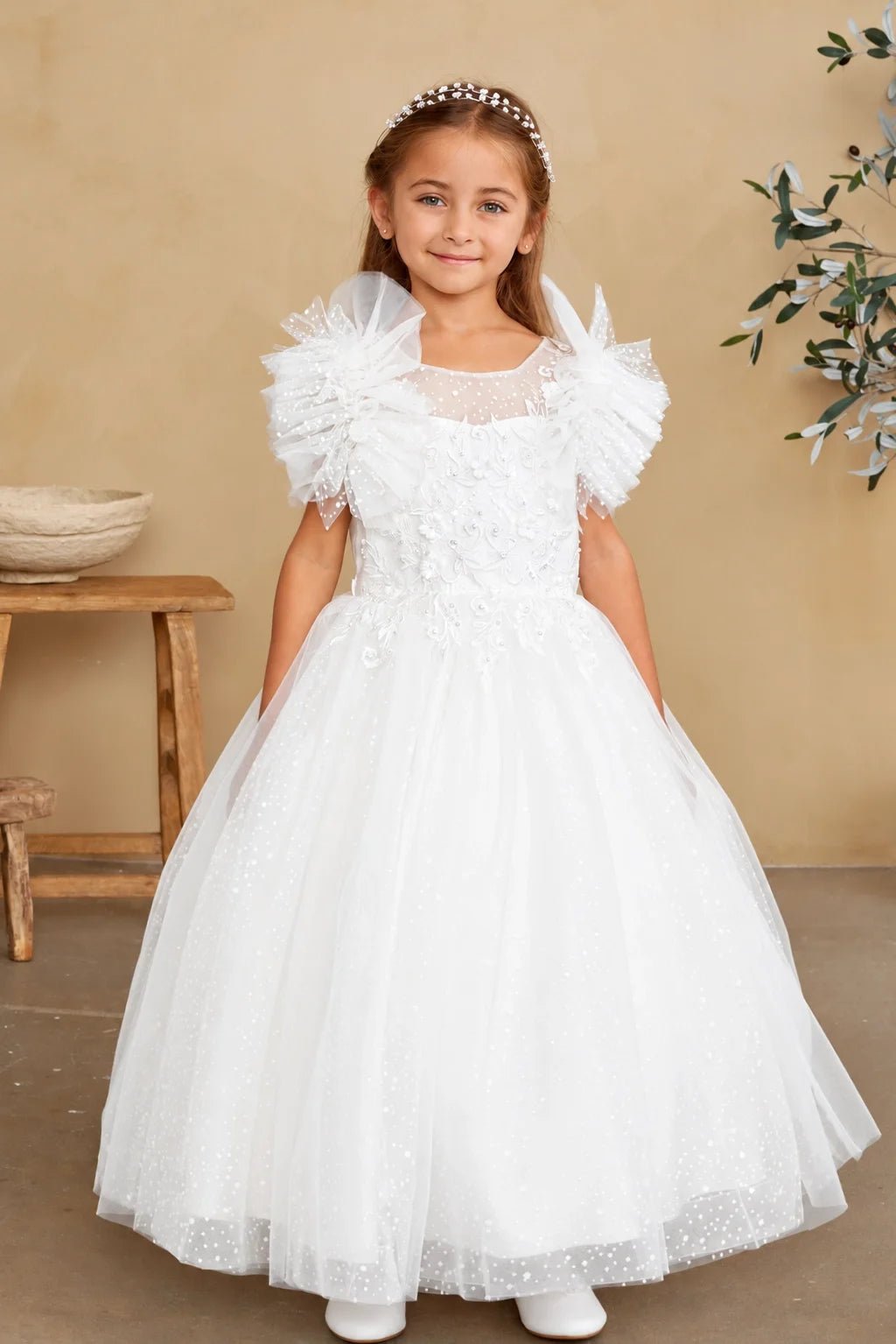 Fanned tulle ruffles crown the shoulders of an off-white flower girl dress.