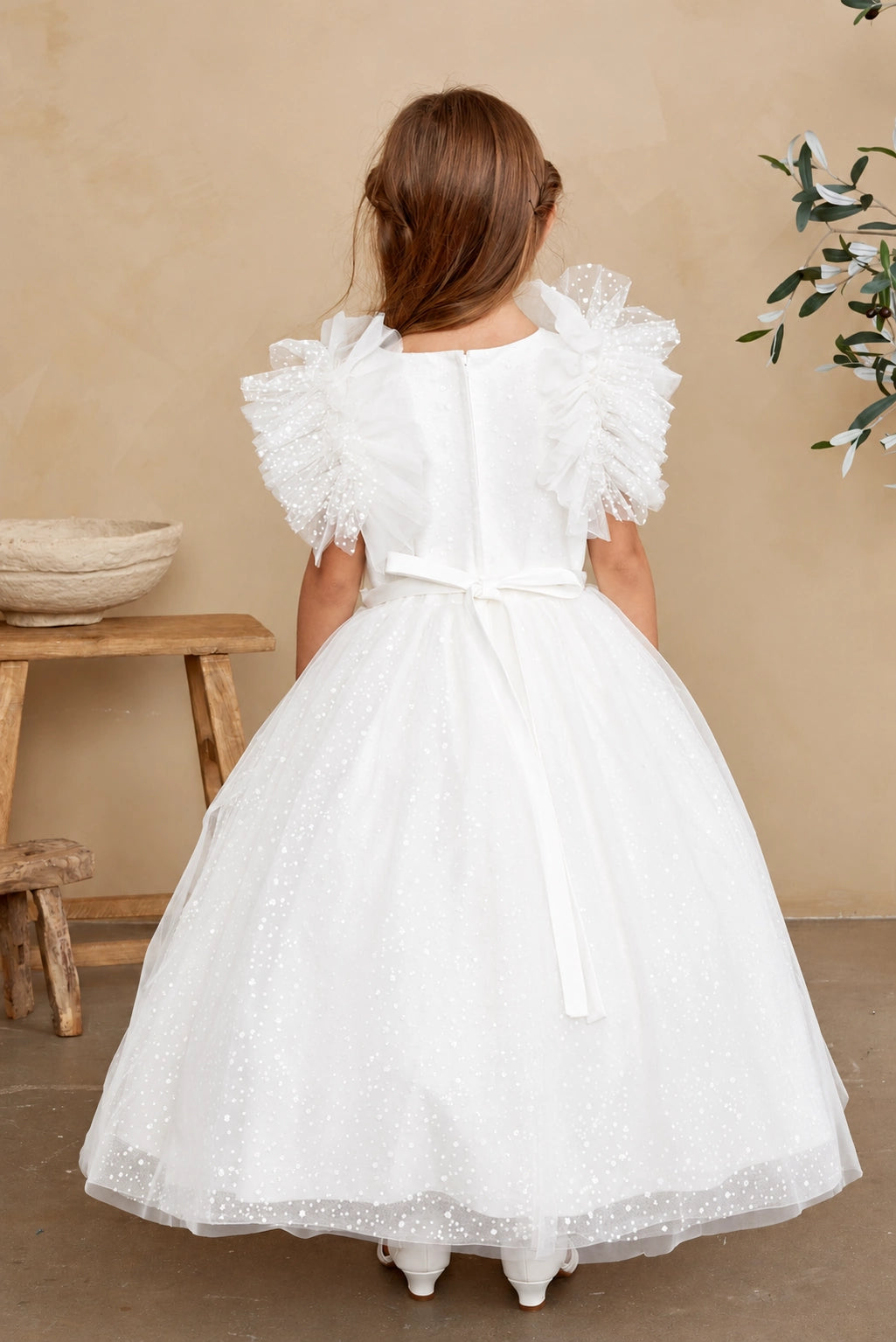 Emphasis on a small satin back bow of the off-white flower girl dress.