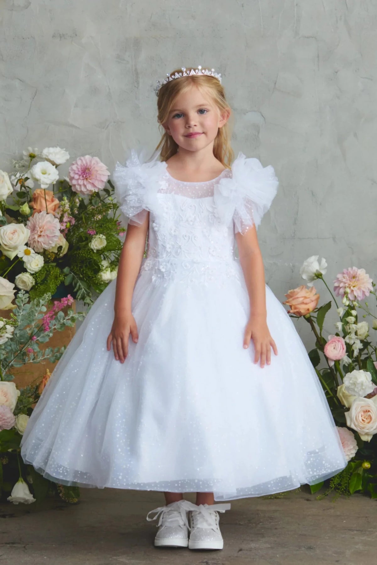 Dotted tulle peeks beyond the white flower girl dress's skirt hem.