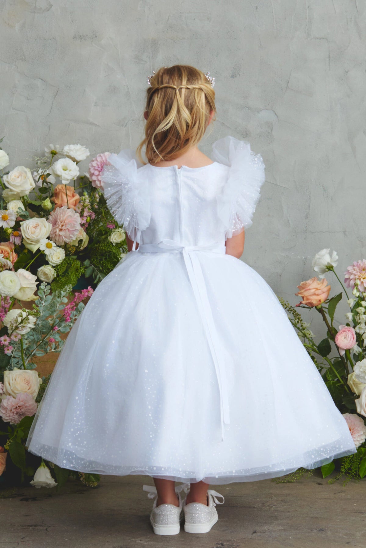 A view of a satin waist bow on the white flower girl dress.