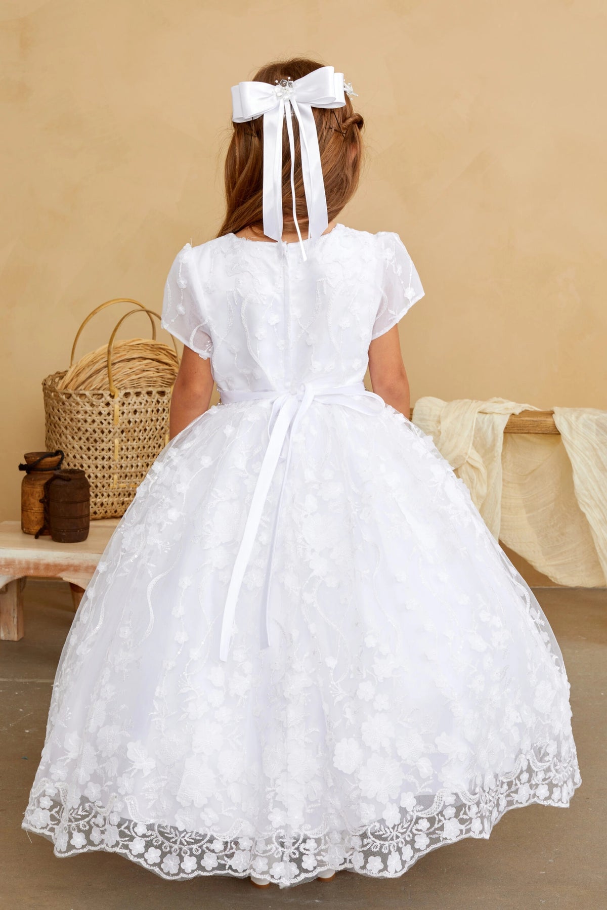 Detailed with a satin sash bow, this white flower girl dress.