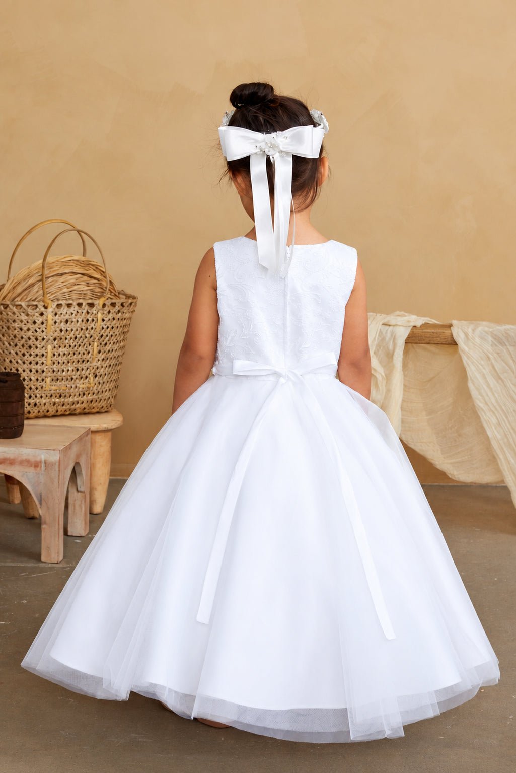 A small satin bow rests at the white flower girl dress's back waist.