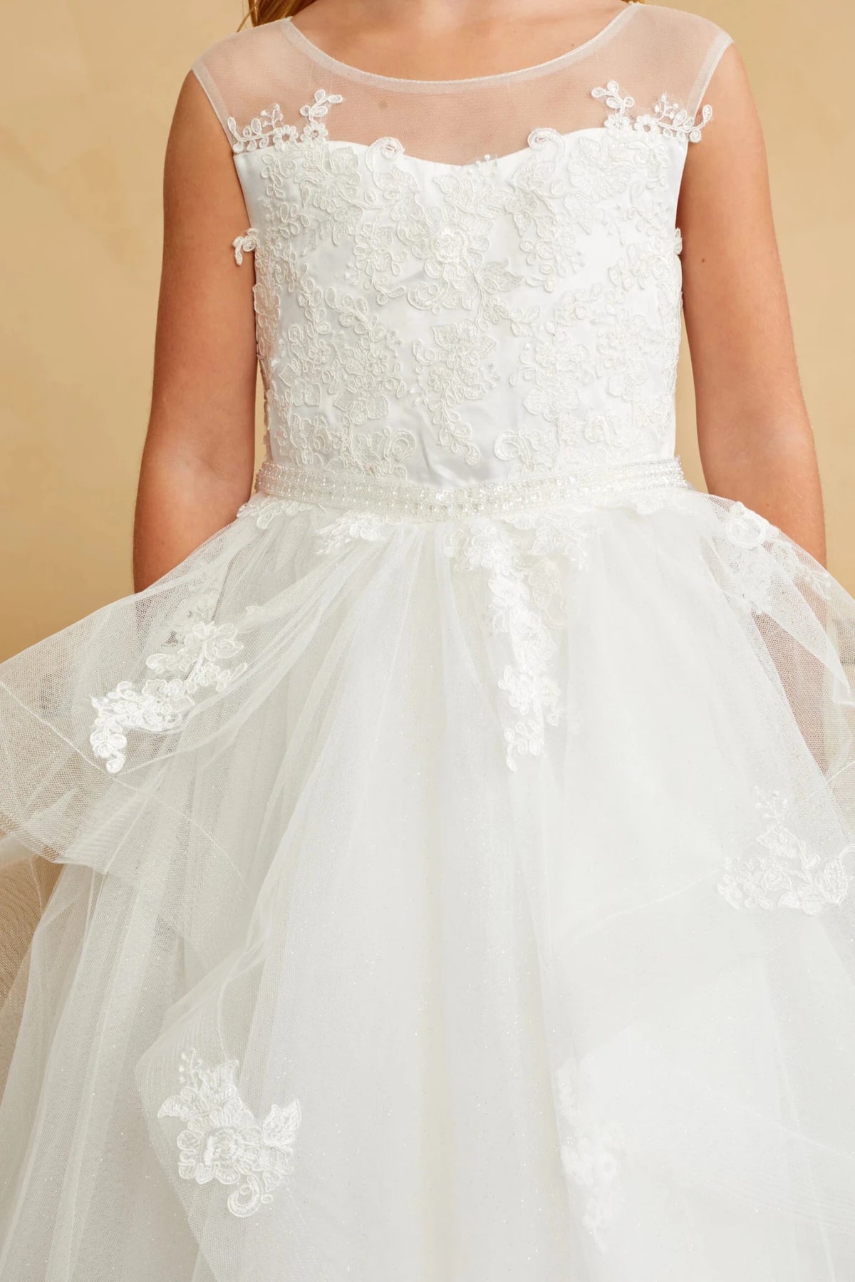 Just below the waist, off-white flower girl dress lace trims a pointed fold.