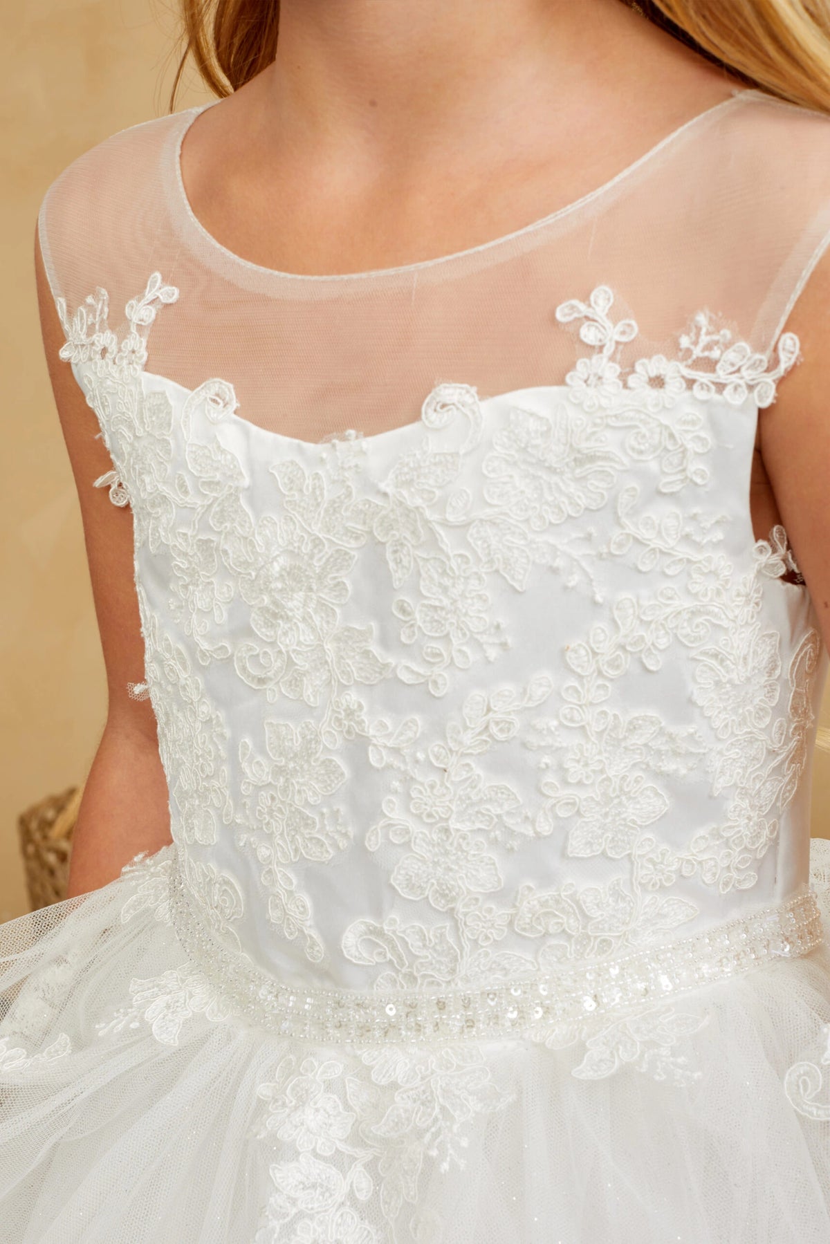 Embroidered sprigs extend past the off-white flower girl dress's bodice edge.