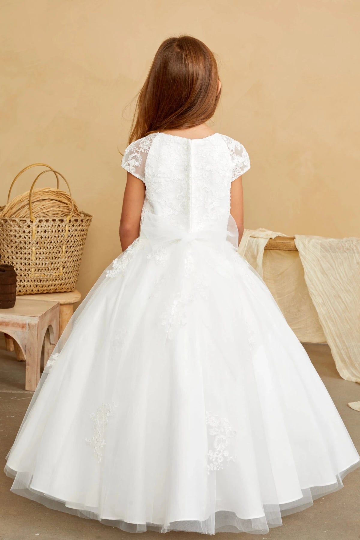 At the back, an off-white flower girl dress has a small satin waist bow.
