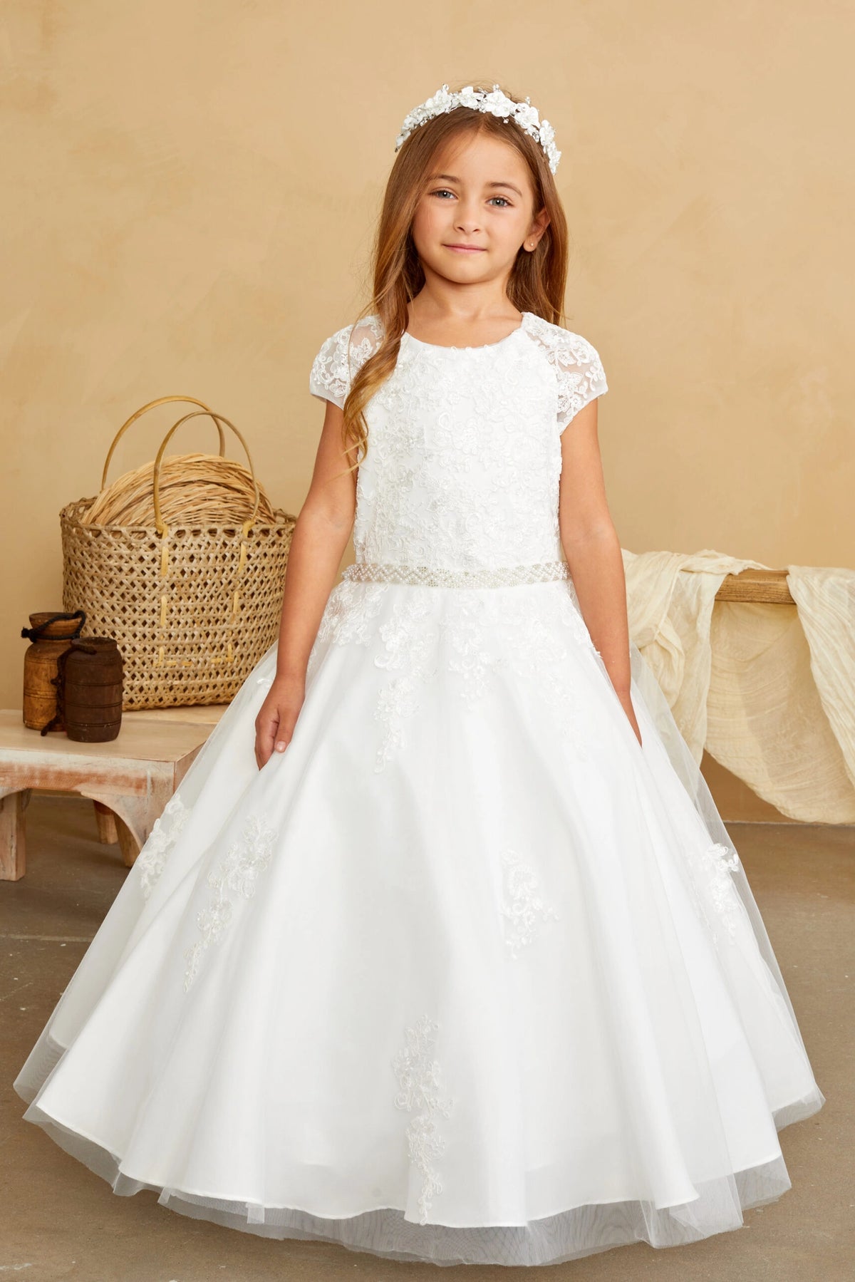 Lace motifs taper down the off-white flower girl dress's skirt.