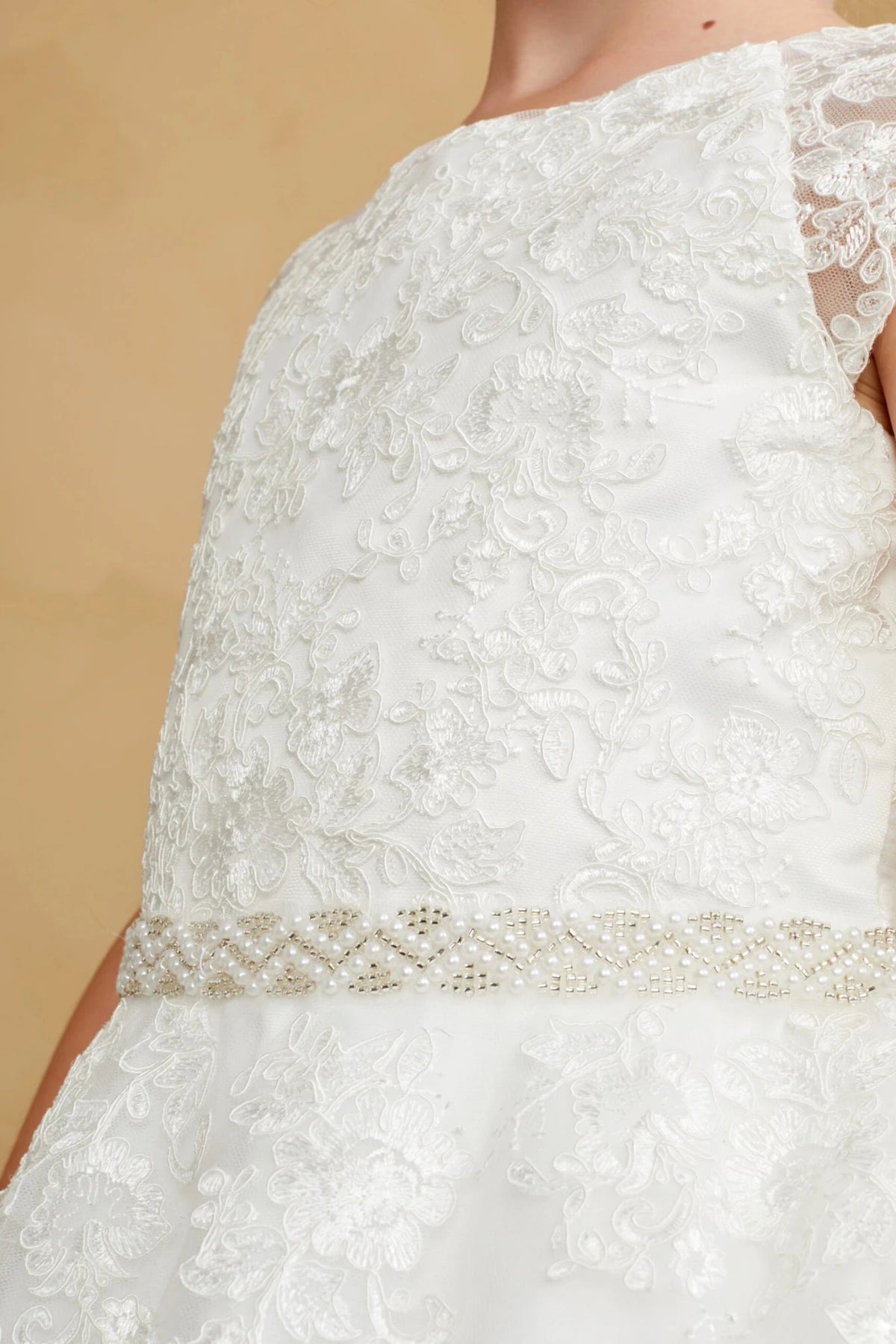 Diamond-pattern beading circles the off-white flower girl dress's waist.
