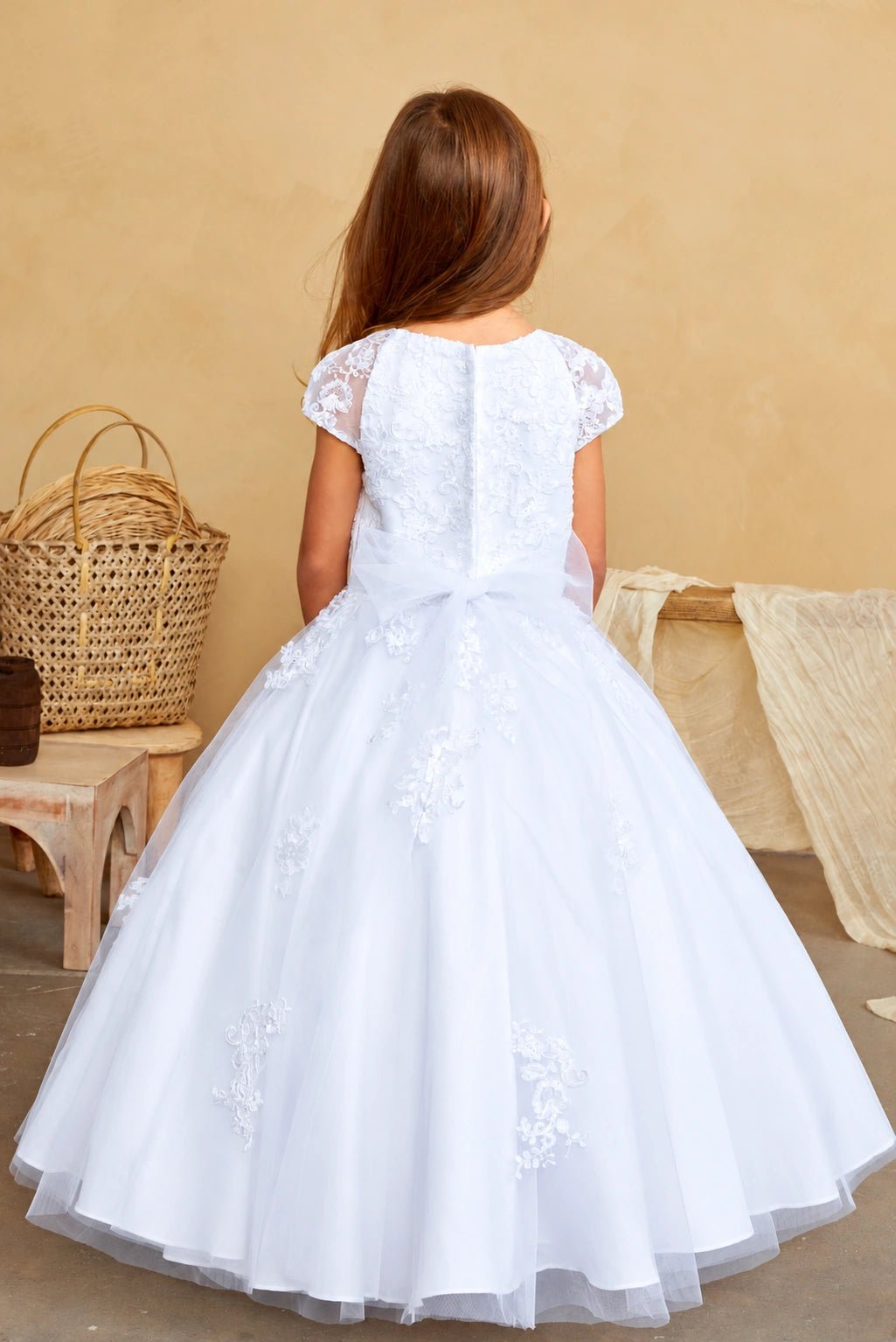 From behind, the white flower girl dress shows trailing floral appliques.