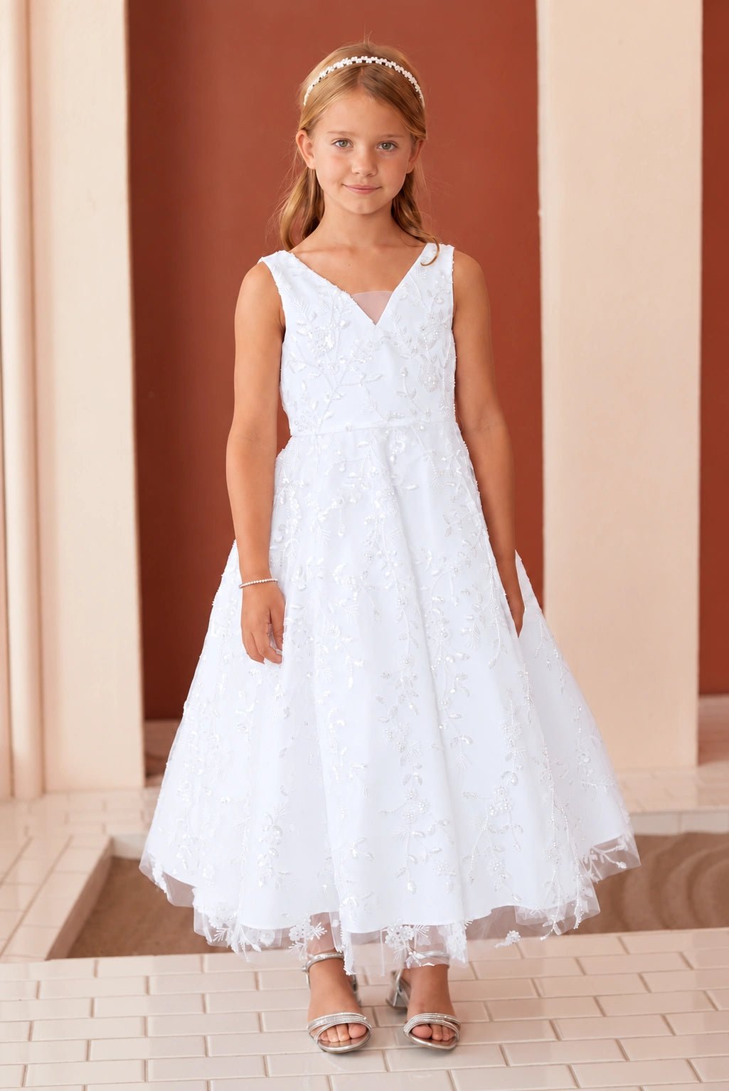 Allover blossoms texture the white flower girl dress's flared skirt.