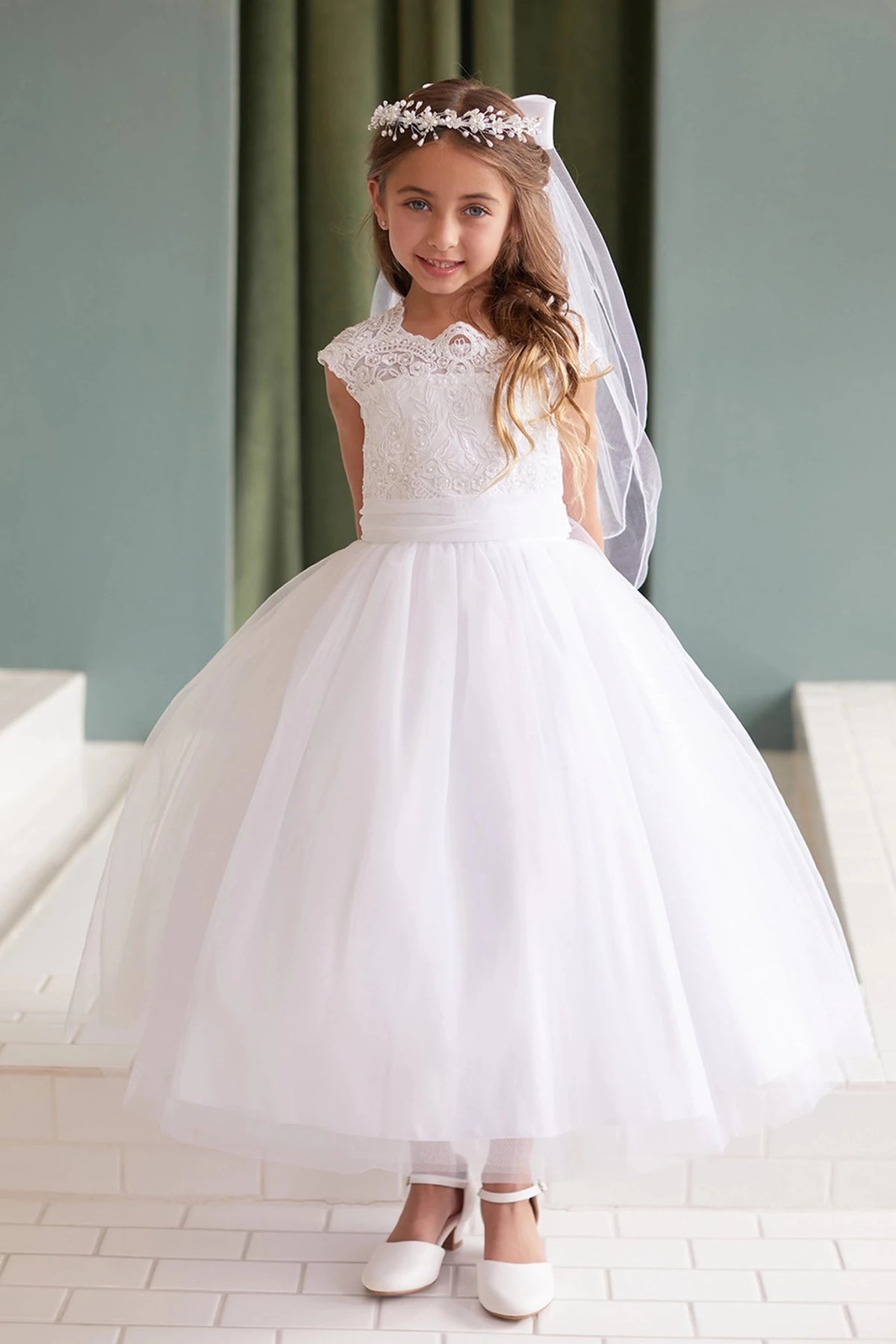 Focus on a full gathered tulle skirt of the white flower girl dress.