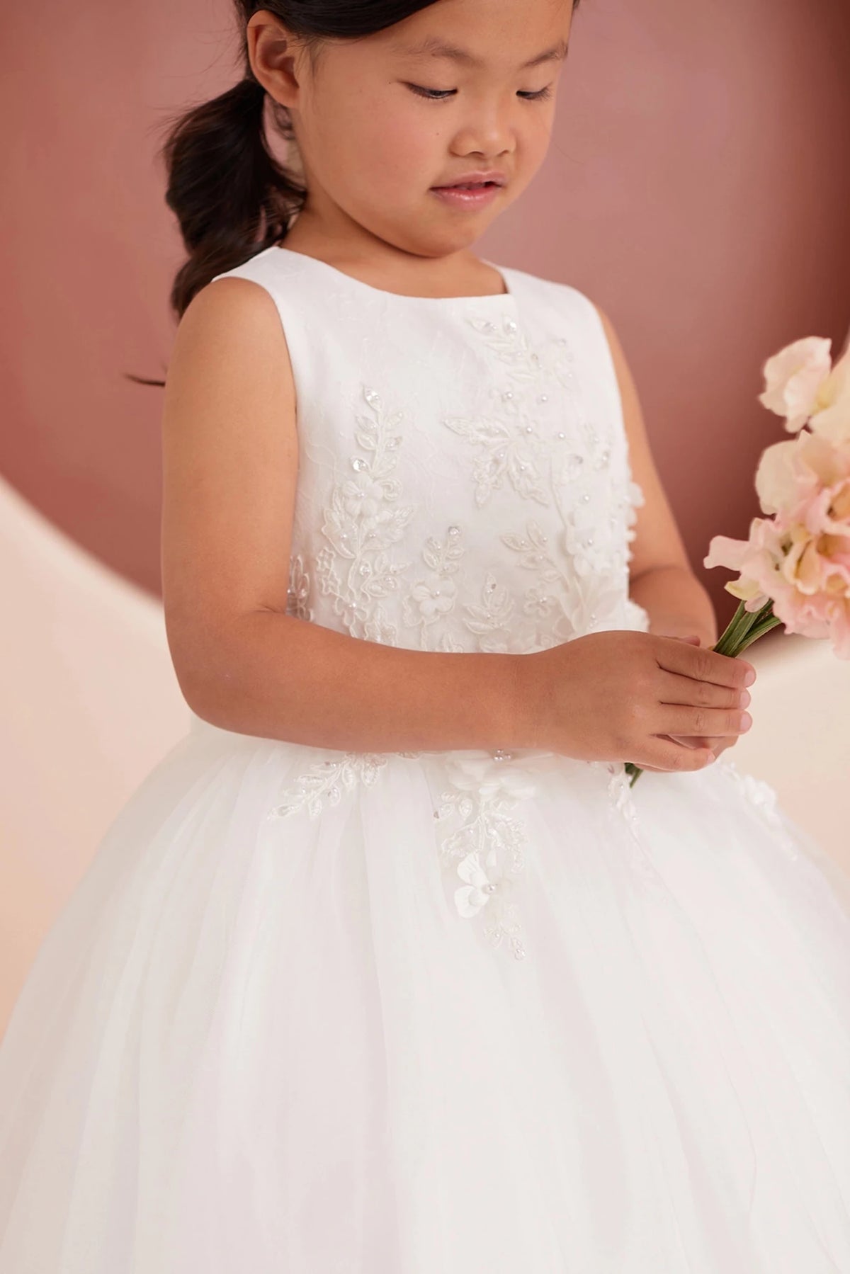 Close-up of the ivory 3d floral lace with a bow back flower girl dress.
