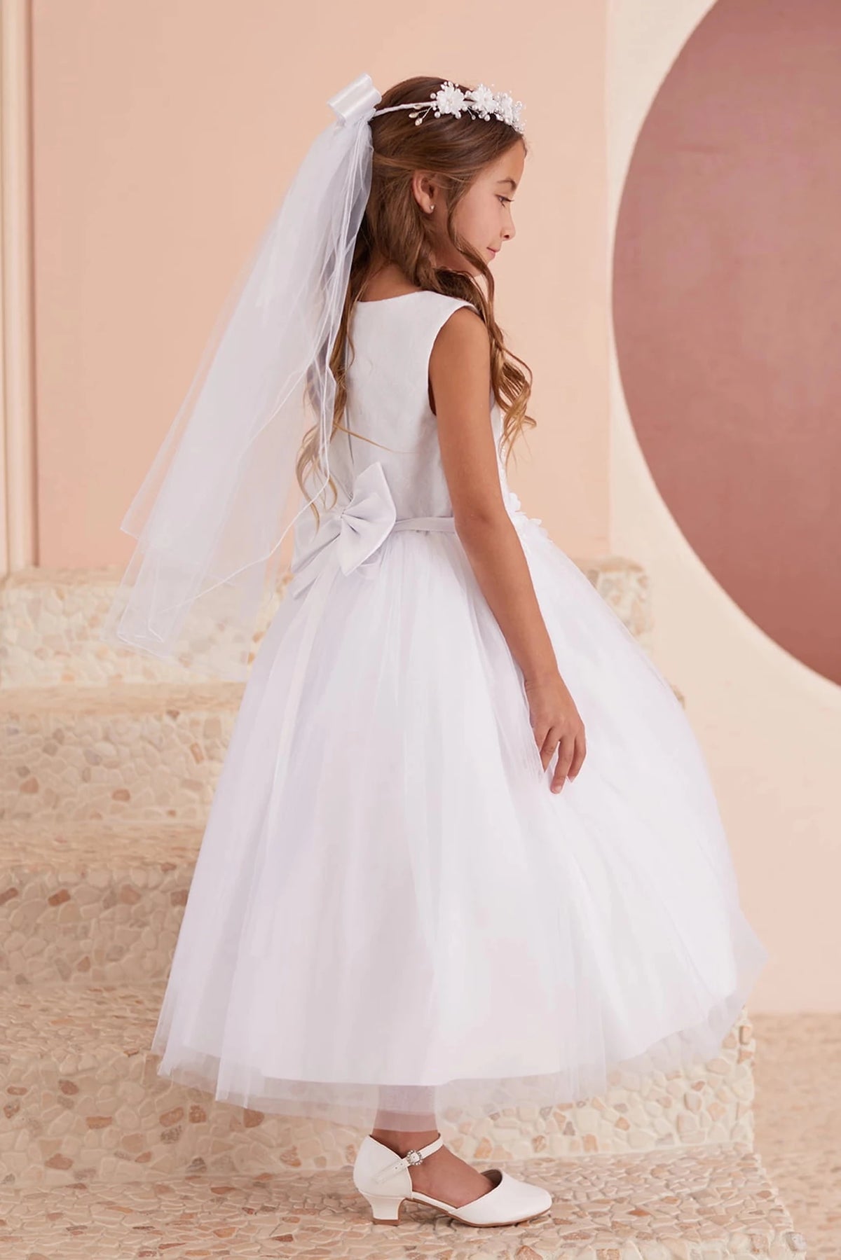A view of a scalloped lace hem on the white flower girl dress.