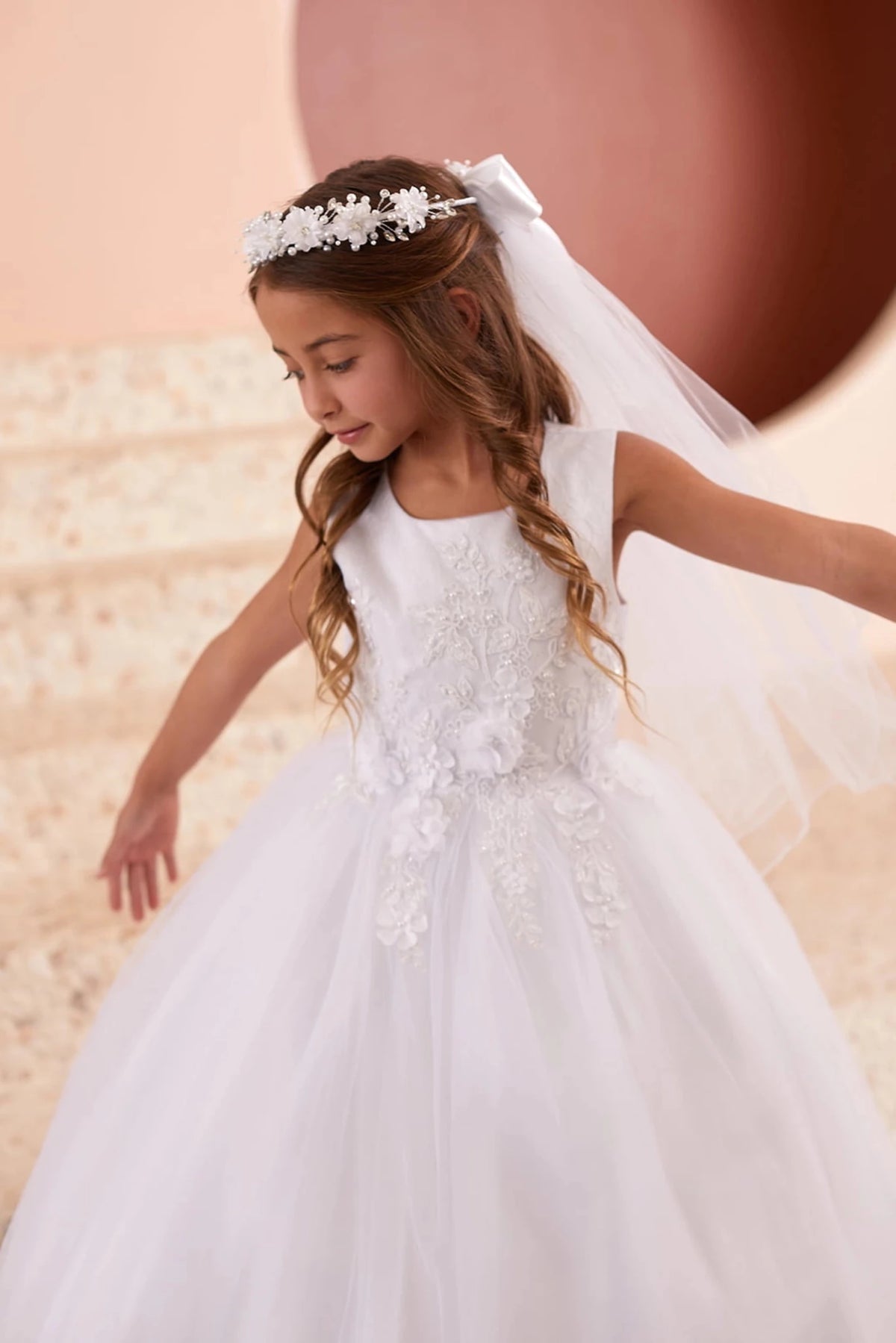 Floral skirt appliques accent the white flower girl dress.