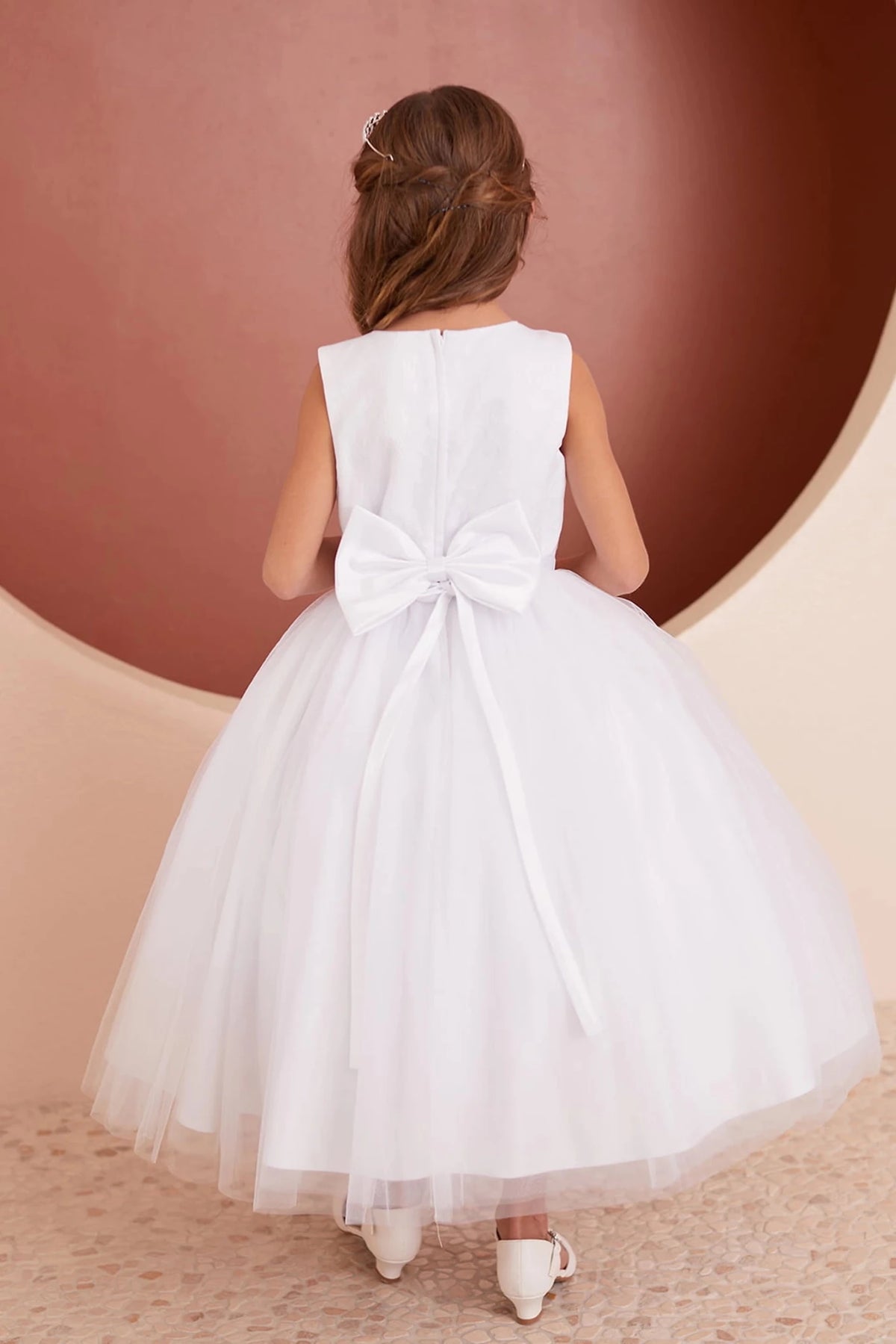 Defined by a satin back bow, this white flower girl dress.