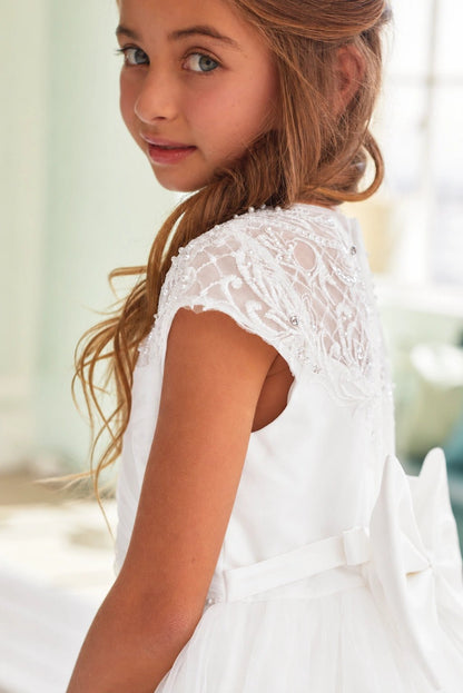 Open lace forms a curved cap sleeve on this off-white flower girl dress.