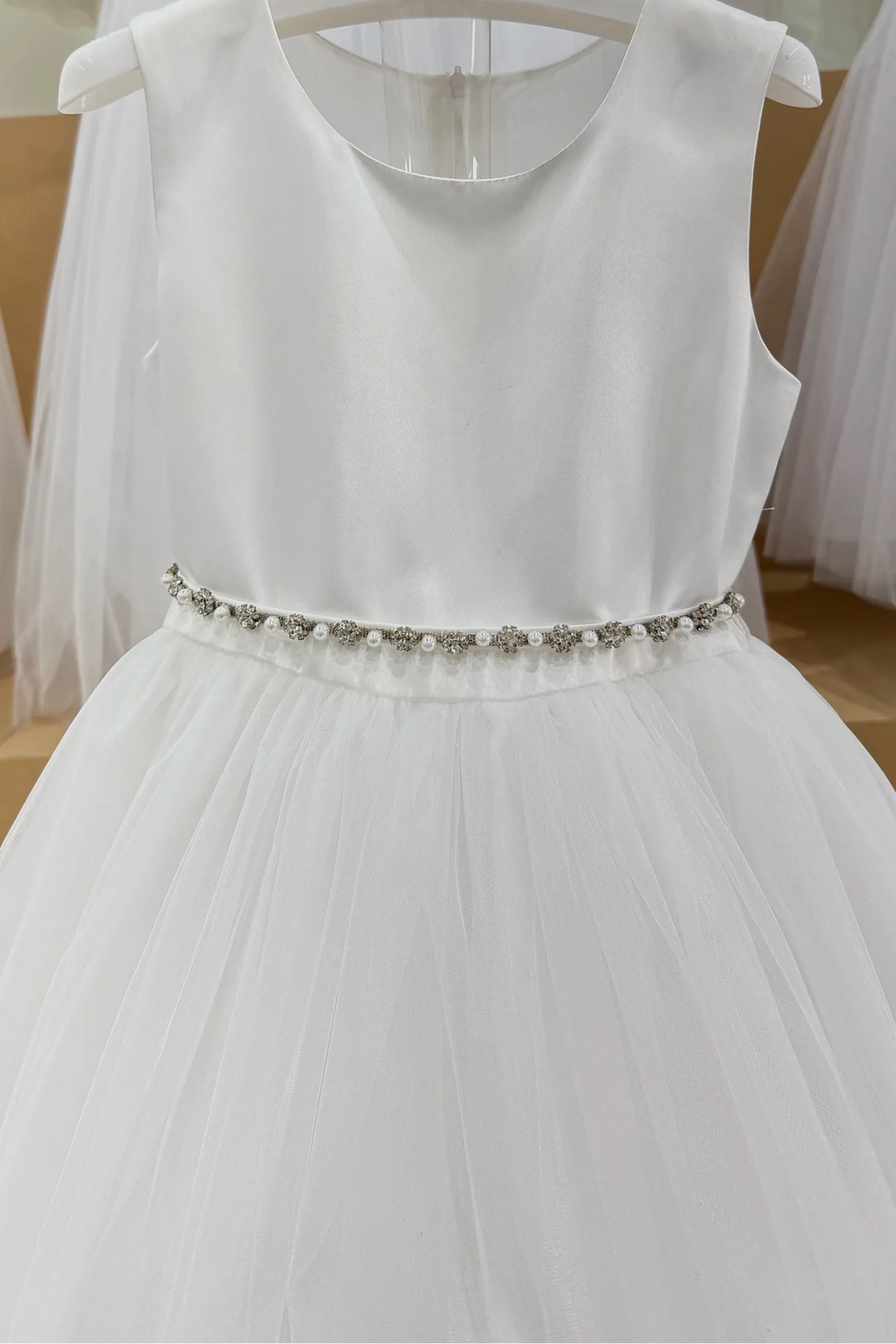 Close-up of the sleeveless satin bodice, pearl-and-crystal waistband and gathered tulle on Tiptop 5863 off-white flower girl dress.