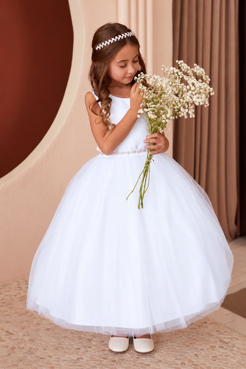 Tiptop 5863 white satin and tulle flower girl dress shown on a child holding a bouquet, with a delicate pearl-and-crystal waistband.