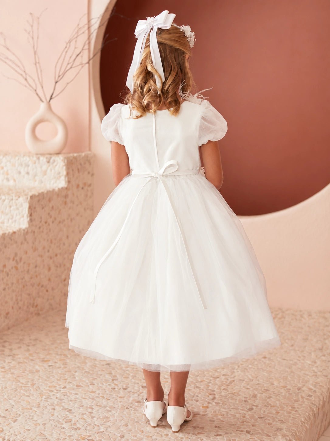 On this off-white flower girl dress, a small satin back bow is visible.