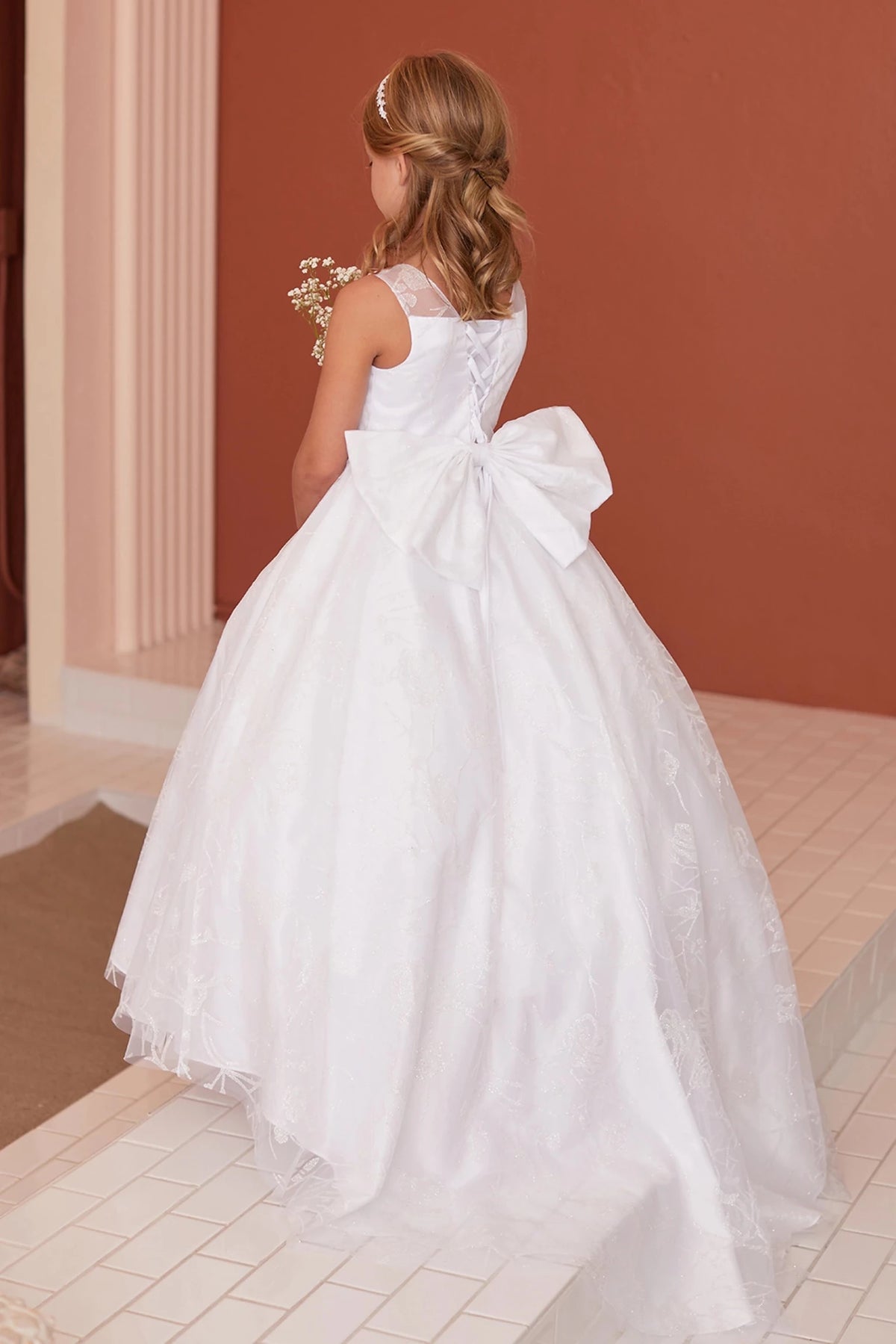 Broad bow loops spread across the off-white flower girl dress's back waist.