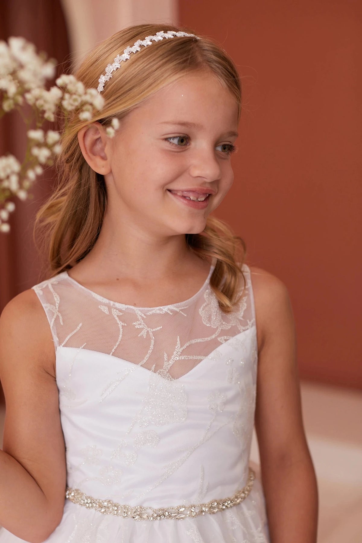 Pleated fabric crosses the off-white flower girl dress's sweetheart bodice.