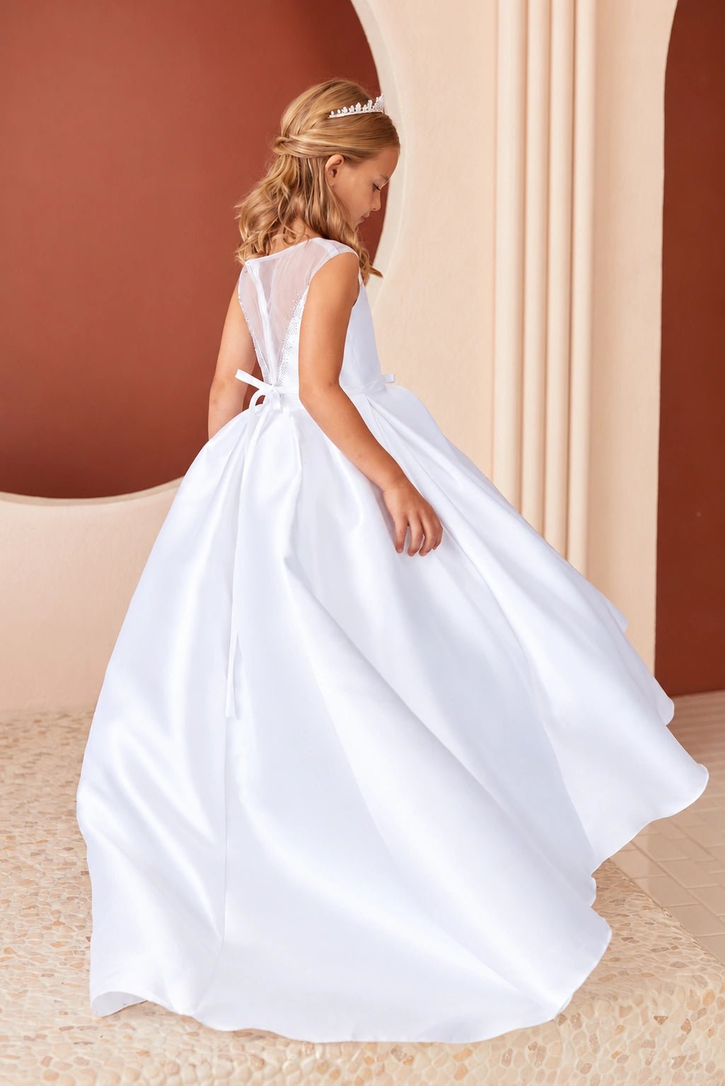 Satin spills into a long train behind this white flower girl dress.
