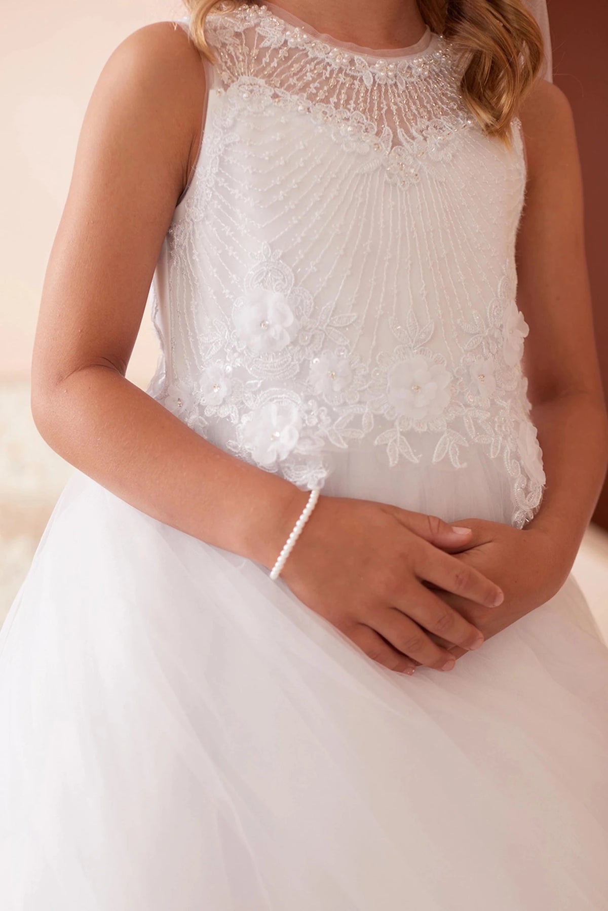 Diagonal bodice pleats accent the white flower girl dress.