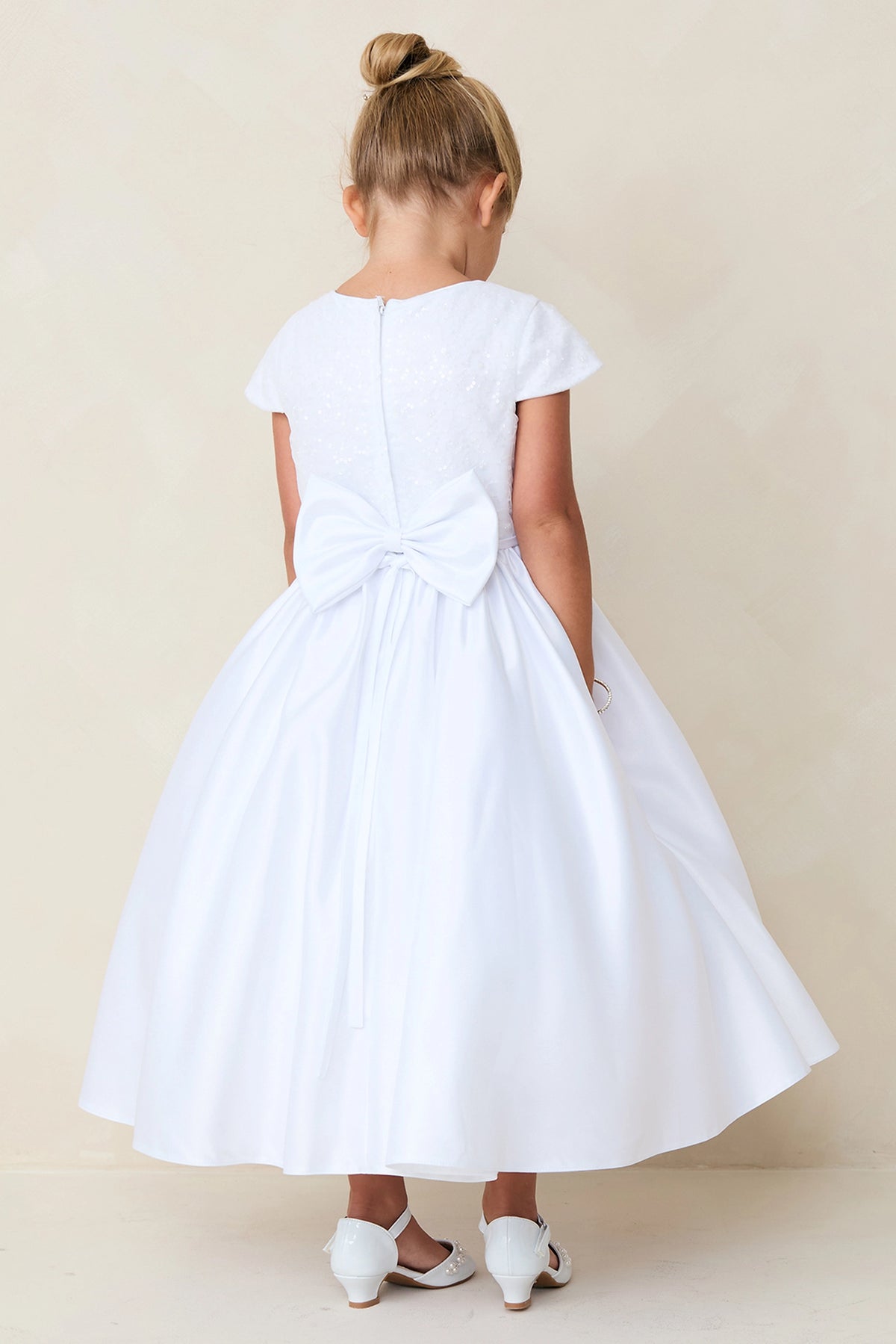With a large satin back bow, a white flower girl dress.