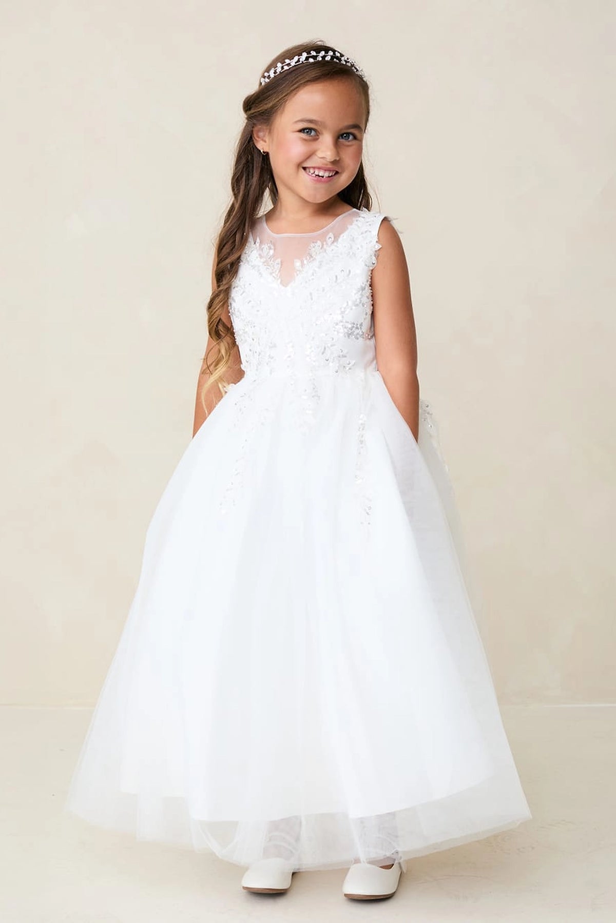 Raised lace flowers edge the off-white flower girl dress's V neckline.