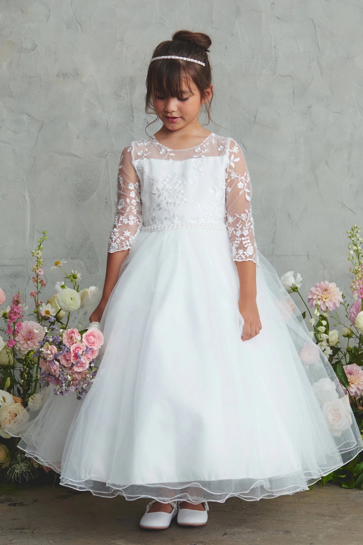Focus on a layered mesh hem of the white flower girl dress.
