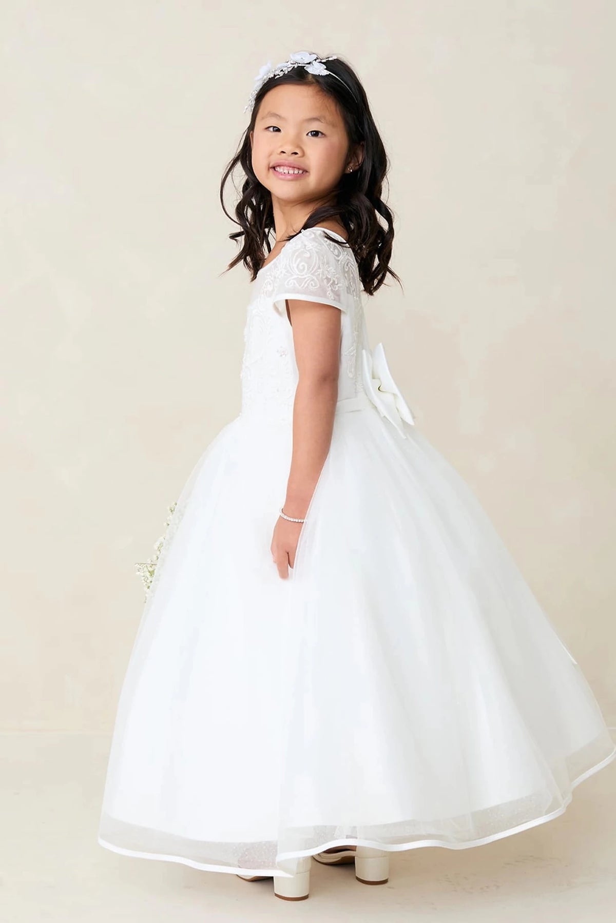 Emphasis on lace cap sleeves of the off-white flower girl dress.