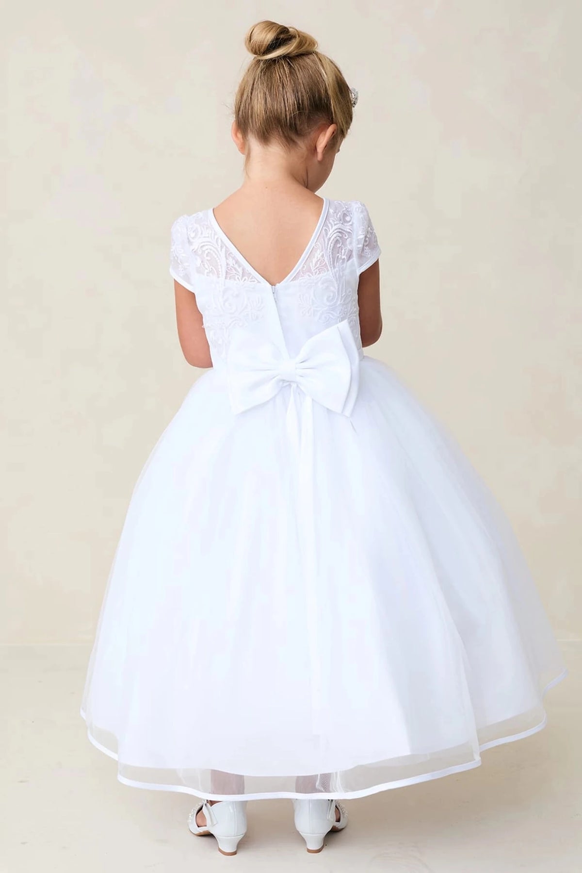Highlighting V-shaped back on a white flower girl dress.
