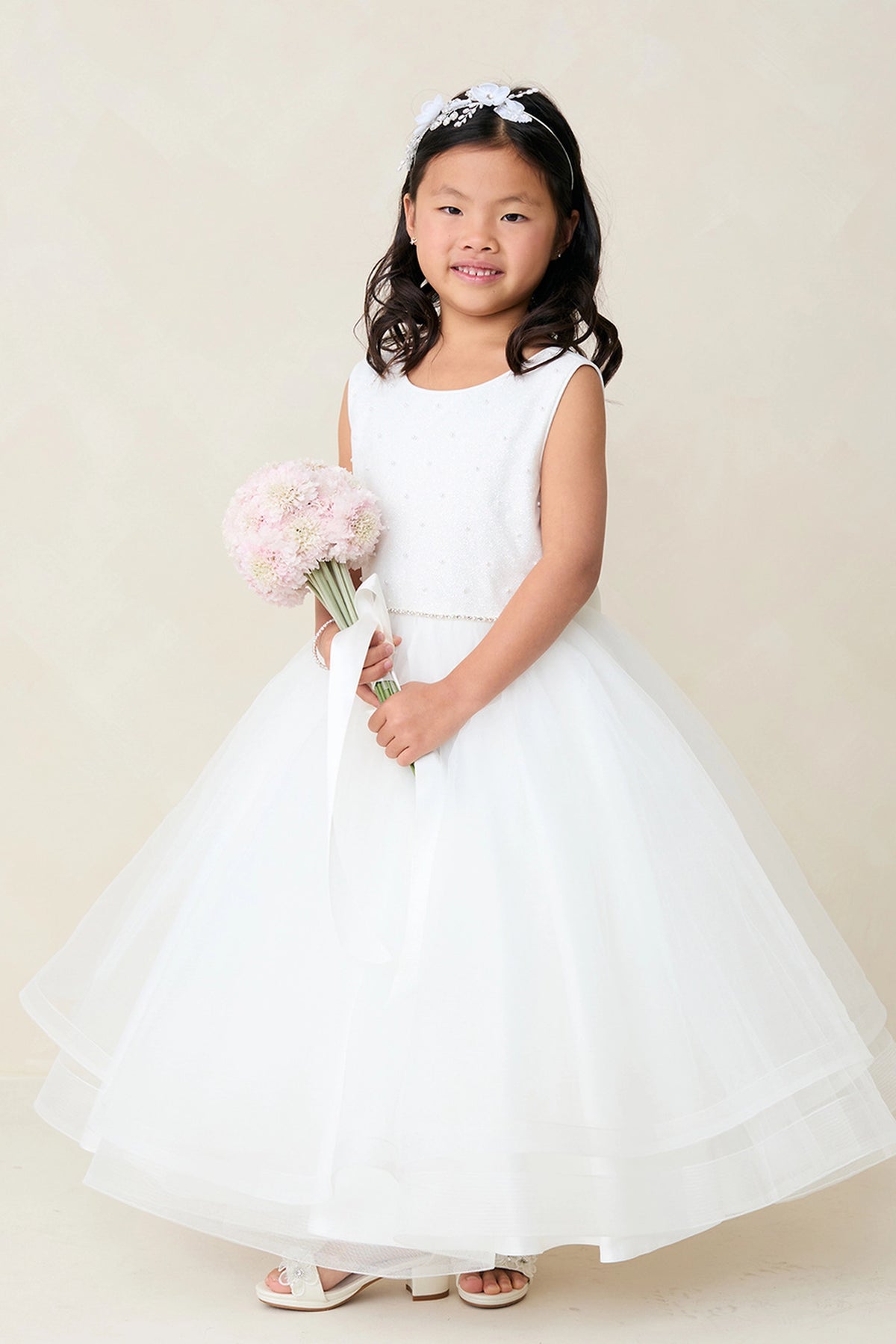 This off-white flower girl dress displays a fine pleated skirt.