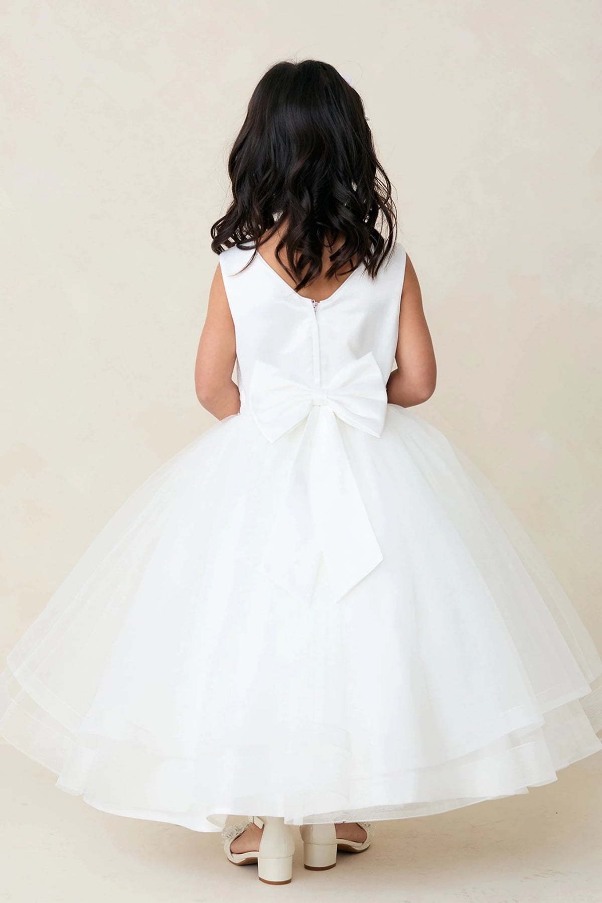 Large satin back bow accents the off-white flower girl dress.