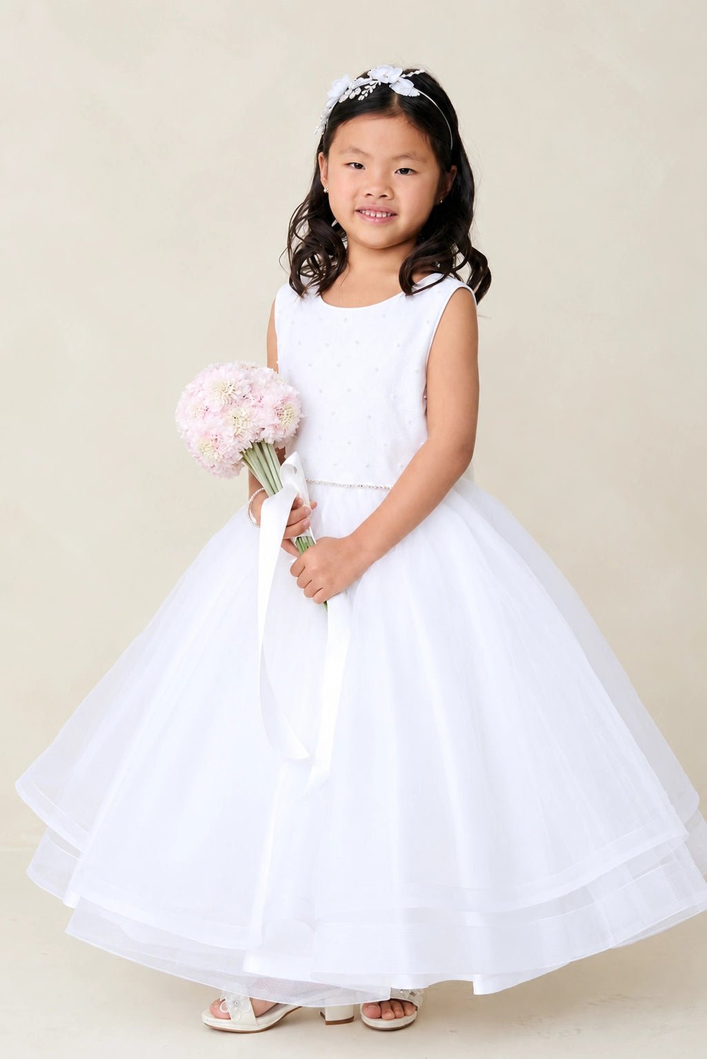 The white flower girl dress features a layered mesh hem.