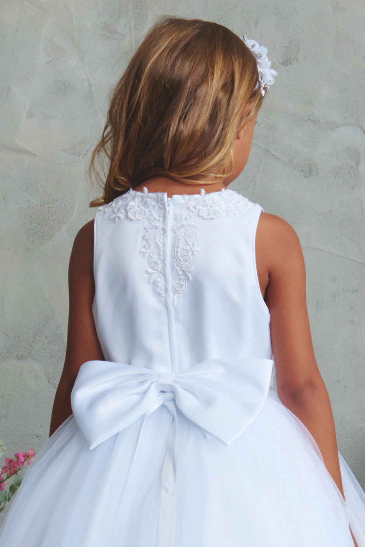 Emphasis on a scalloped rear neckline of the white flower girl dress.