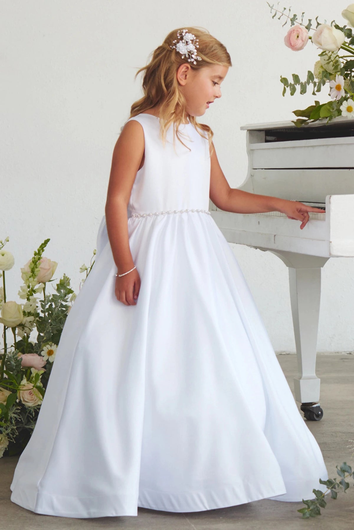 Smooth sleeveless bodice accents this white flower girl dress.