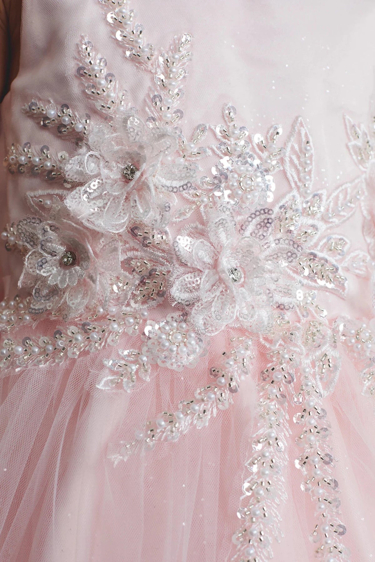 A view of 3D beaded flowers on the blush flower girl dress.