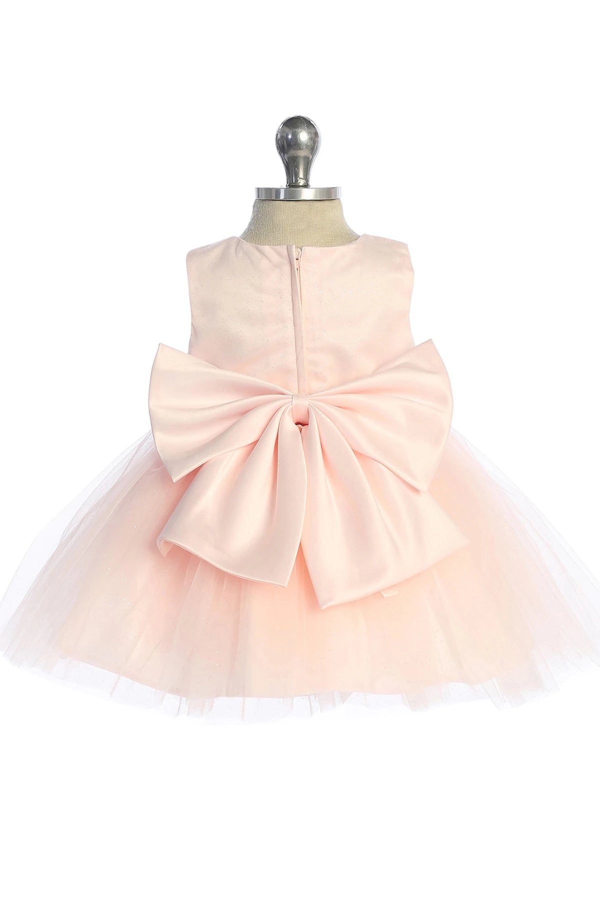 Highlighting a large satin bow on a blush flower girl dress.